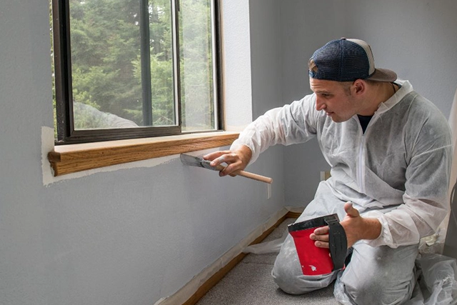 Painter in Protective Clothing Staining Window Trim in San Jose