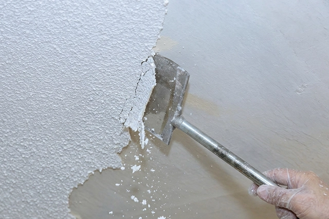 Hand Removing Popcorn Ceiling with Tool for Painting Contractors
