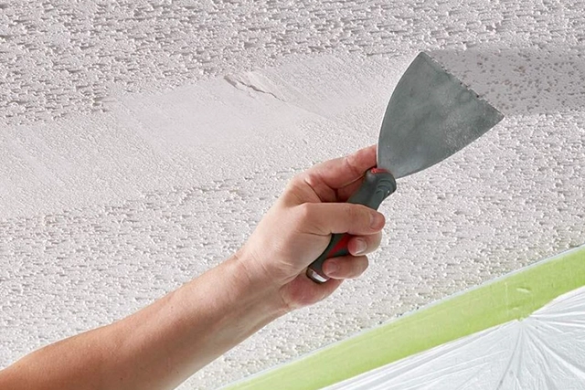 Hand Scraping Popcorn Ceiling Smooth With a Metal Tool
