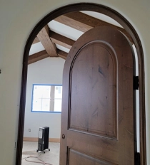 Wooden Doorway Leading to Unfinished Room with Arched Ceiling Beams