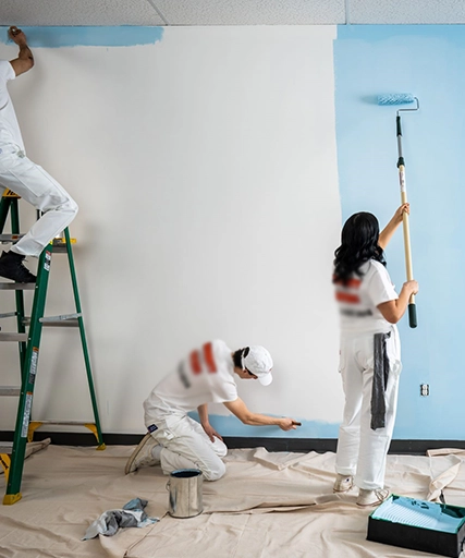 Painters Working on Blue and White Walls with Rollers and Brushes