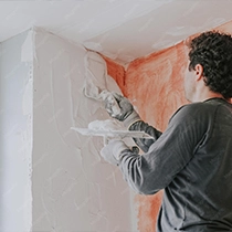 Person Applying Plaster to Wall Corner with Trowel